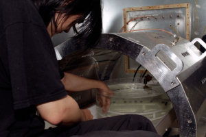 Working with professor Ji Chen, graduate student Kevin Feng sits on the MRI machine with his hand inside of the phantom.